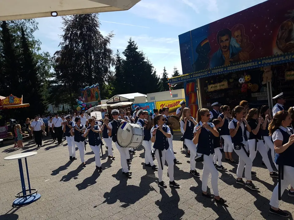 Das Tambourkorps spielt auf dem Schützenplatz zwischen Karussell und Fahrgeschäften