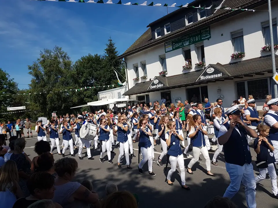 Flötistinnen und Trommler des Tambourkorps ziehen dicht an der Zuschauermenge vorbei durch den Ort